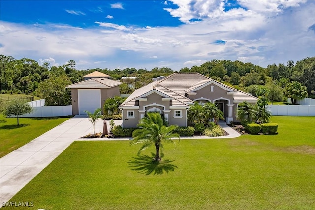 mediterranean / spanish home featuring a front yard, concrete driveway, fence, and a tiled roof