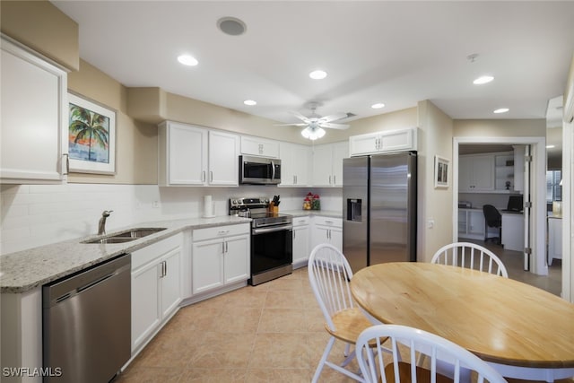 kitchen featuring light tile patterned flooring, appliances with stainless steel finishes, decorative backsplash, ceiling fan, and white cabinetry