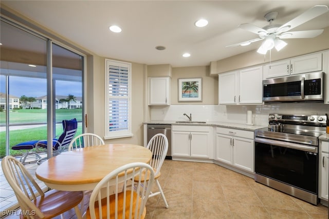 kitchen featuring white cabinetry, backsplash, appliances with stainless steel finishes, and light tile patterned floors