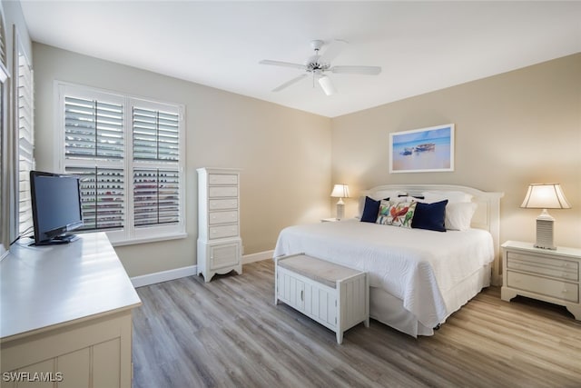 bedroom with light wood-type flooring, a ceiling fan, and baseboards