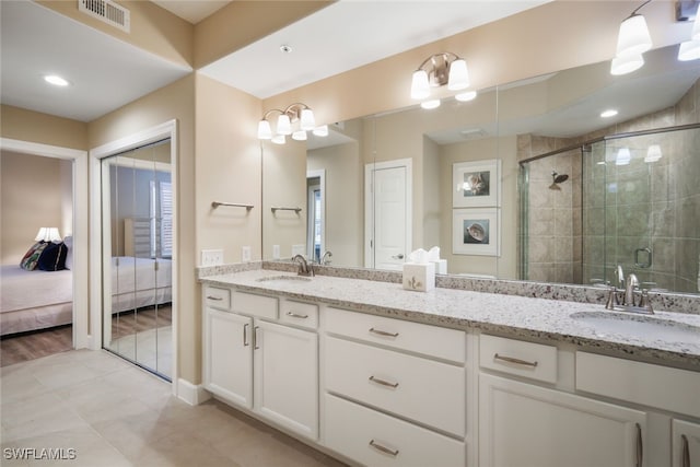 bathroom with tile patterned flooring, a shower with shower door, and vanity