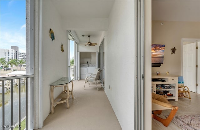 hall with light colored carpet, separate washer and dryer, and a water view