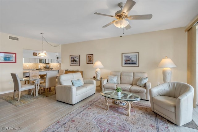 living room with ceiling fan and light hardwood / wood-style flooring