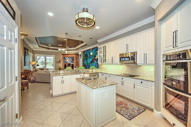 kitchen with light stone counters, a center island with sink, white cabinets, and appliances with stainless steel finishes