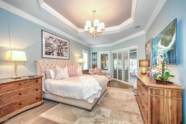 bedroom with a chandelier, light wood-type flooring, a raised ceiling, and ornamental molding