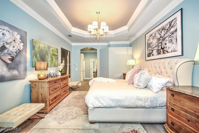 bedroom featuring a tray ceiling, an inviting chandelier, hardwood / wood-style flooring, and ornamental molding