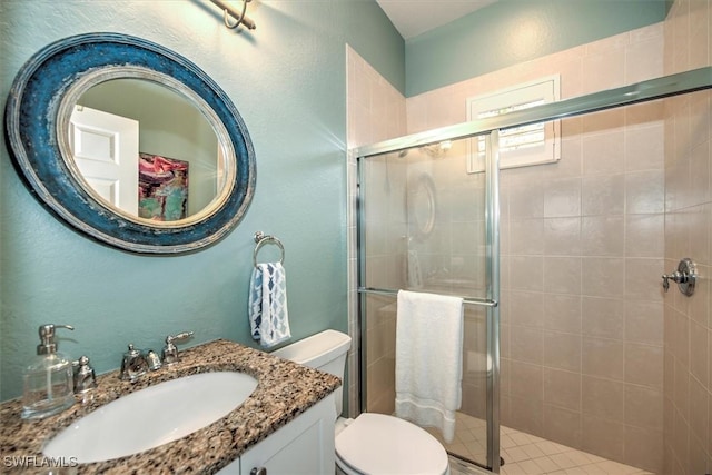 bathroom with tile patterned floors, vanity, toilet, and walk in shower