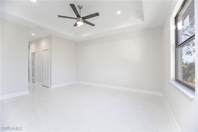 spare room with a raised ceiling and ceiling fan