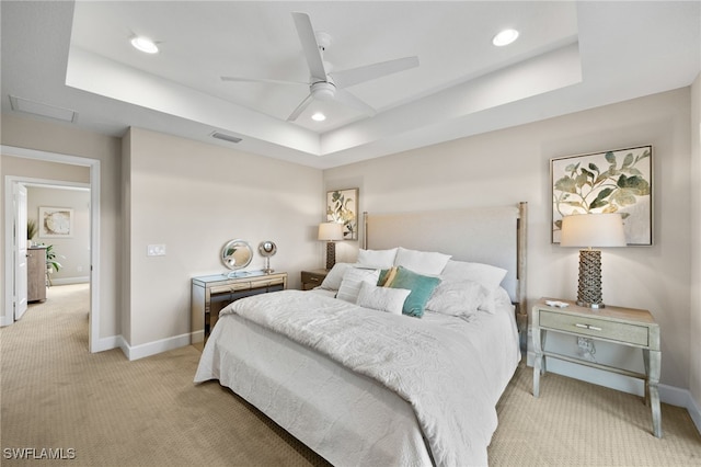 bedroom with a tray ceiling, light colored carpet, and ceiling fan