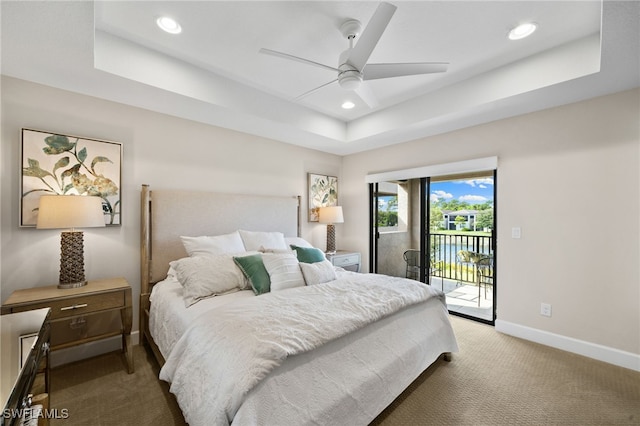 carpeted bedroom featuring access to exterior, ceiling fan, and a tray ceiling