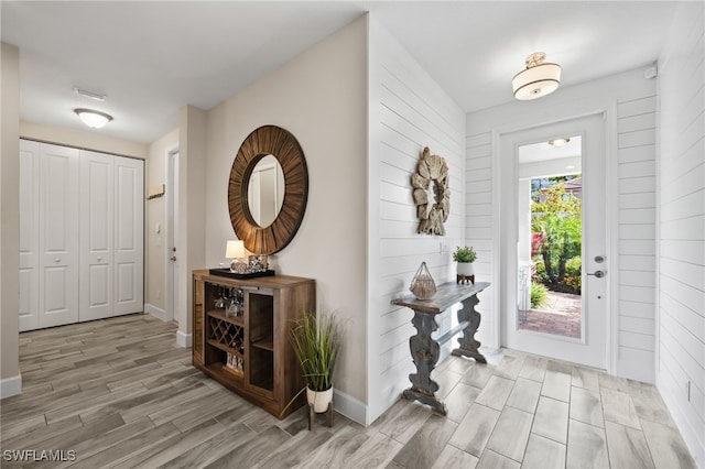 foyer entrance with light hardwood / wood-style flooring and wooden walls