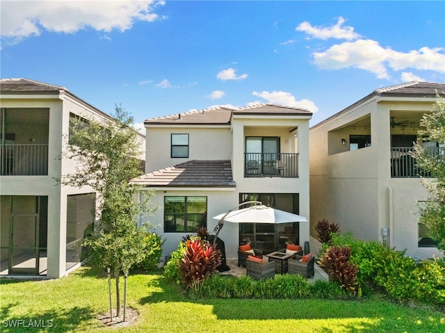 back of property with a lawn, a patio area, an outdoor hangout area, and a balcony