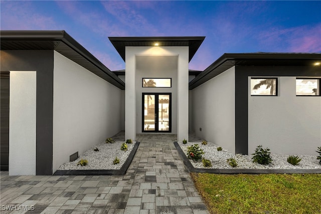 exterior entry at dusk with a patio and french doors