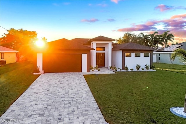 prairie-style house featuring a lawn, decorative driveway, and stucco siding