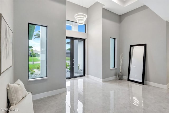 foyer featuring a high ceiling, baseboards, a wealth of natural light, and french doors