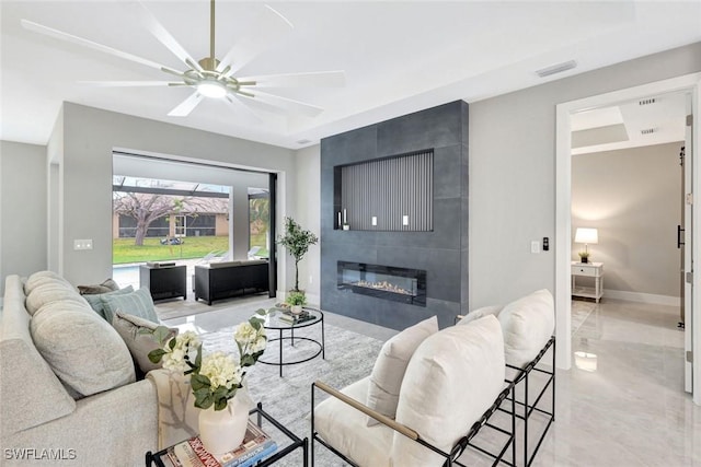 living area with a large fireplace, a ceiling fan, visible vents, and baseboards