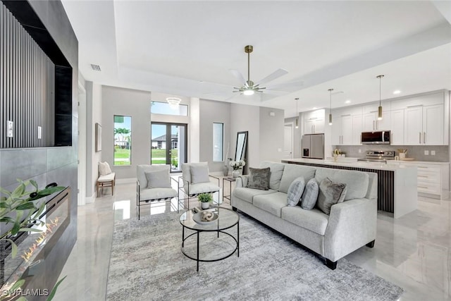 living room with ceiling fan, recessed lighting, visible vents, marble finish floor, and a tray ceiling