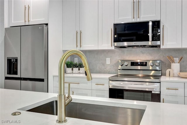 kitchen featuring stainless steel appliances, light countertops, white cabinetry, and tasteful backsplash