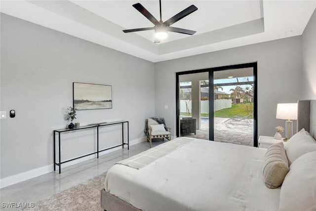 bedroom with finished concrete flooring, baseboards, a ceiling fan, access to outside, and a tray ceiling