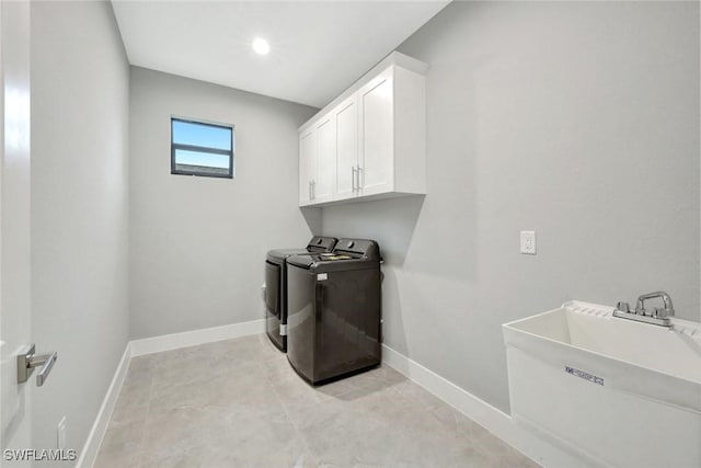 laundry room with cabinet space, baseboards, a sink, and washing machine and clothes dryer