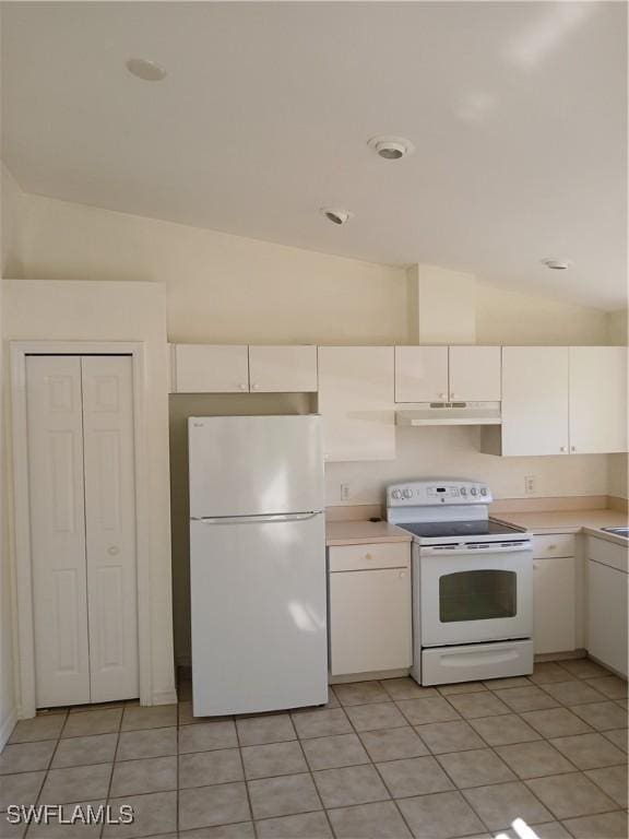 kitchen featuring vaulted ceiling, white cabinetry, light tile patterned floors, and white appliances