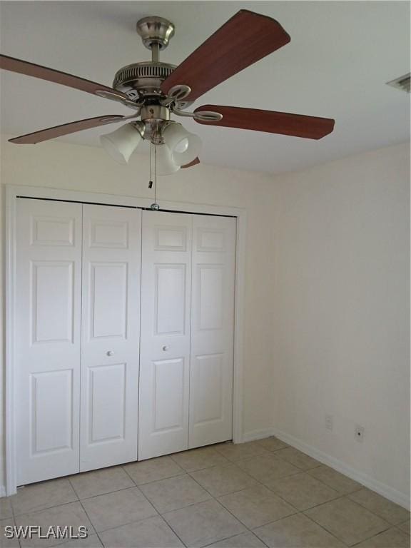 unfurnished bedroom featuring ceiling fan, a closet, and light tile patterned flooring