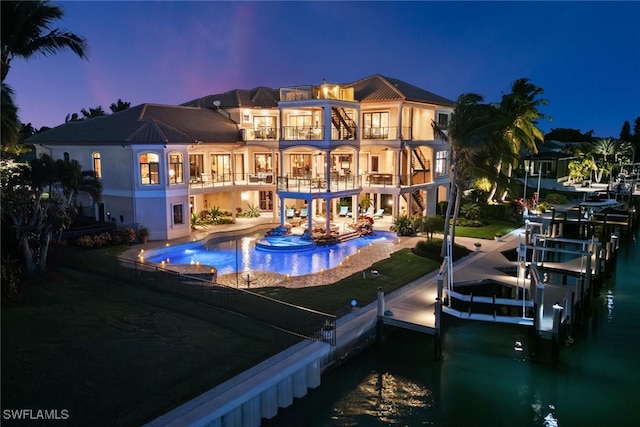 back of house with a patio, a balcony, an outdoor pool, and boat lift