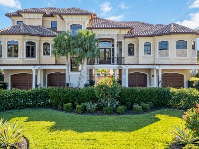 mediterranean / spanish-style house with stucco siding, a tiled roof, and a front yard