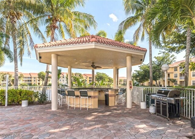 view of patio with ceiling fan, exterior bar, and an outdoor kitchen