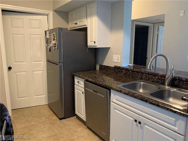 kitchen featuring dishwasher, white cabinetry, sink, light tile patterned floors, and dark stone countertops