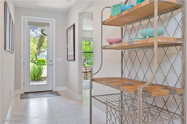 doorway with plenty of natural light, baseboards, and light tile patterned floors