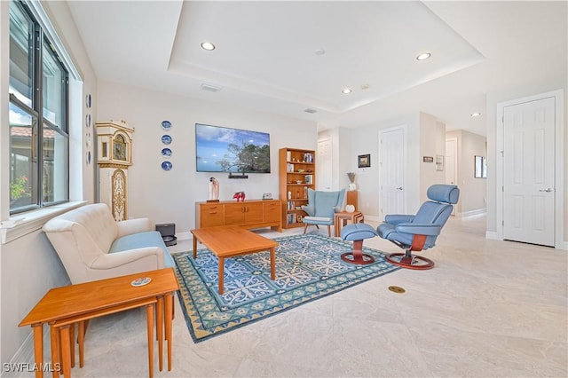 living room featuring recessed lighting, a raised ceiling, and baseboards