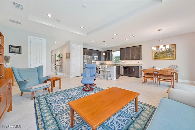 tiled living room with a tray ceiling and a notable chandelier