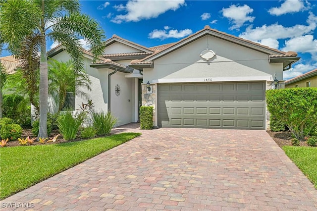 mediterranean / spanish house with a tiled roof, decorative driveway, an attached garage, and stucco siding