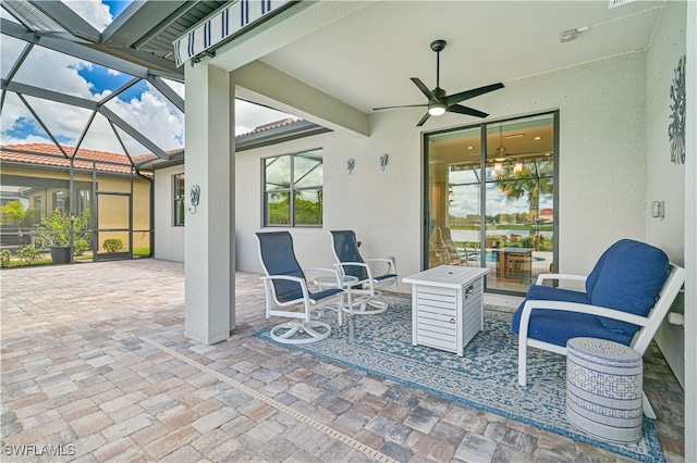 view of patio featuring ceiling fan and glass enclosure