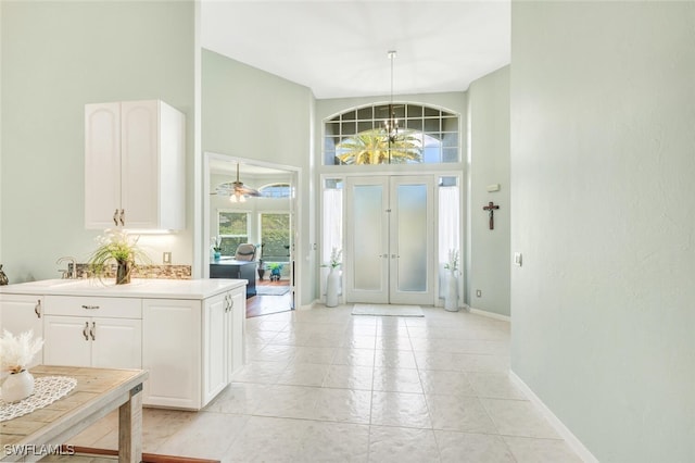 foyer featuring light tile patterned flooring, ceiling fan, and high vaulted ceiling