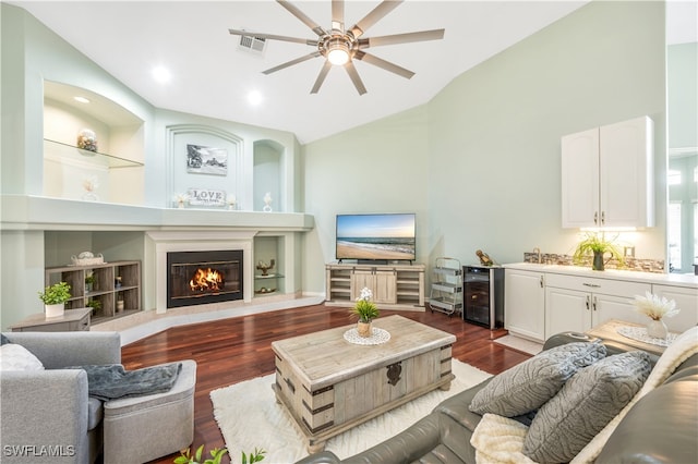 living room with built in shelves, wine cooler, dark wood-type flooring, lofted ceiling, and ceiling fan