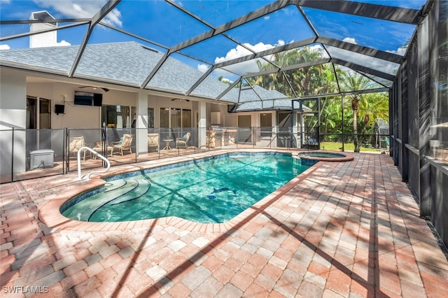 view of pool featuring glass enclosure, a patio, an in ground hot tub, and ceiling fan