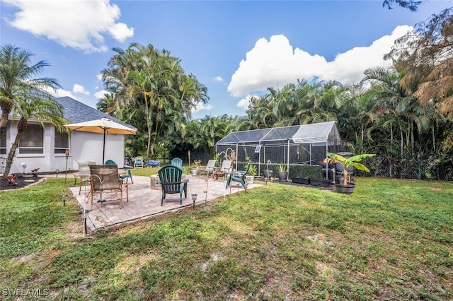 view of yard featuring glass enclosure, a patio area, and a fire pit