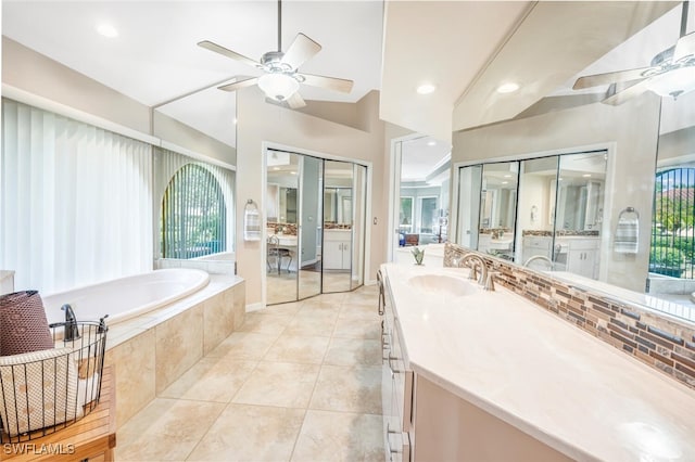 bathroom with tile patterned flooring, plenty of natural light, vanity, and tiled tub