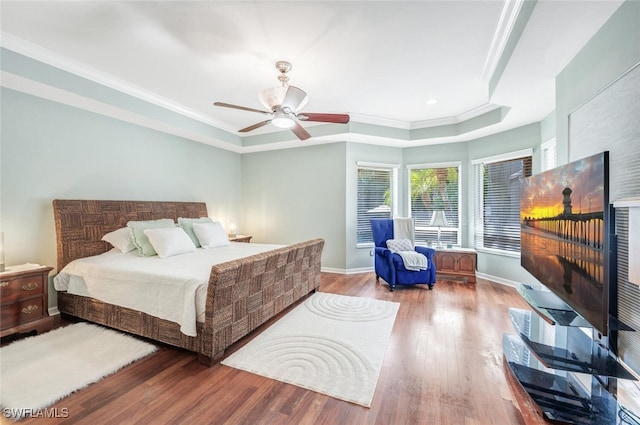 bedroom with crown molding, hardwood / wood-style flooring, ceiling fan, and a raised ceiling