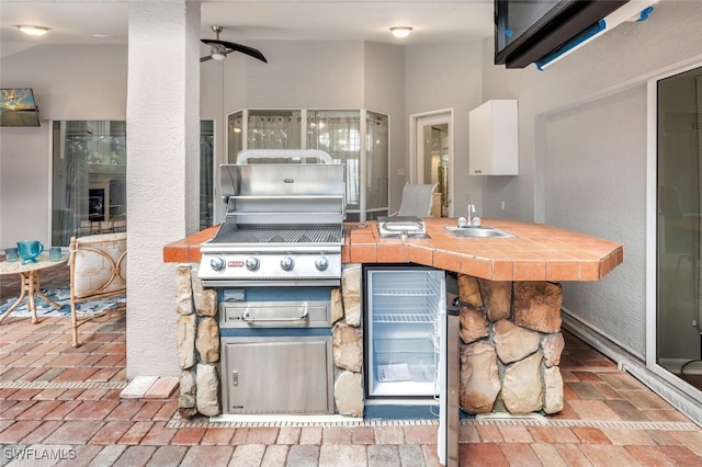 kitchen with tile counters, white cabinetry, and sink