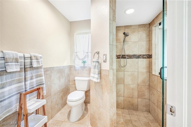 bathroom featuring tile patterned flooring, toilet, tiled shower, and tile walls