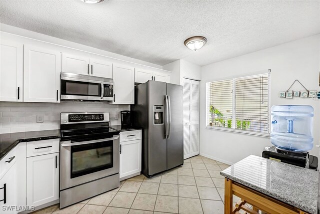 kitchen with decorative backsplash, stainless steel appliances, light tile patterned flooring, and white cabinetry