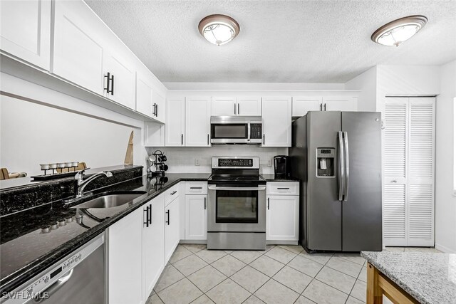 kitchen with sink, stainless steel appliances, white cabinetry, and dark stone counters