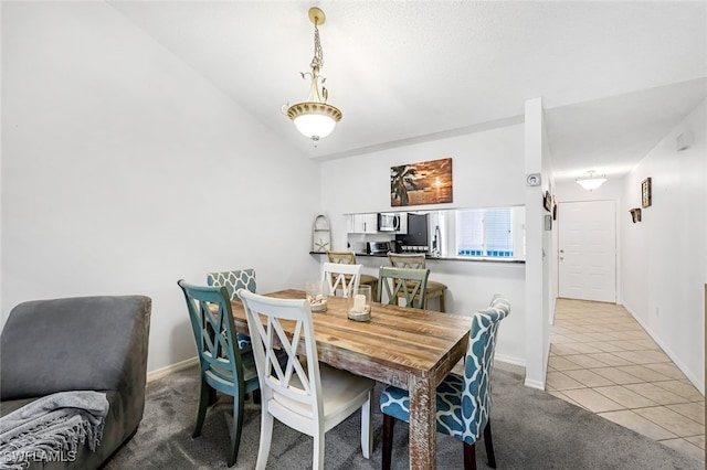 dining room with vaulted ceiling and light carpet