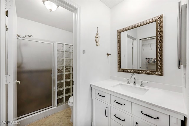 bathroom with tile patterned floors, a shower with door, vanity, and toilet