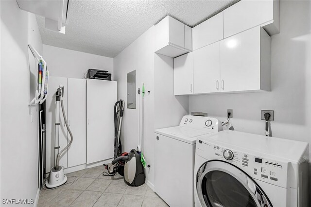 clothes washing area featuring electric panel, washing machine and clothes dryer, a textured ceiling, and cabinets