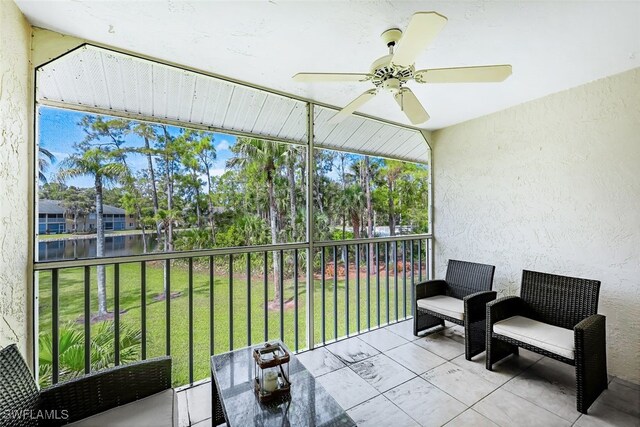 sunroom / solarium featuring ceiling fan and a water view