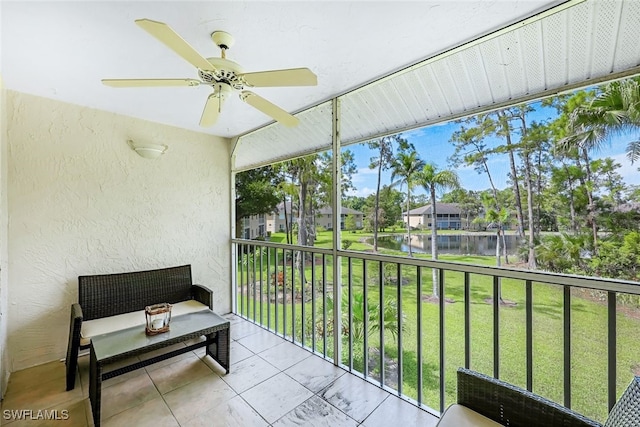 sunroom featuring ceiling fan and a water view